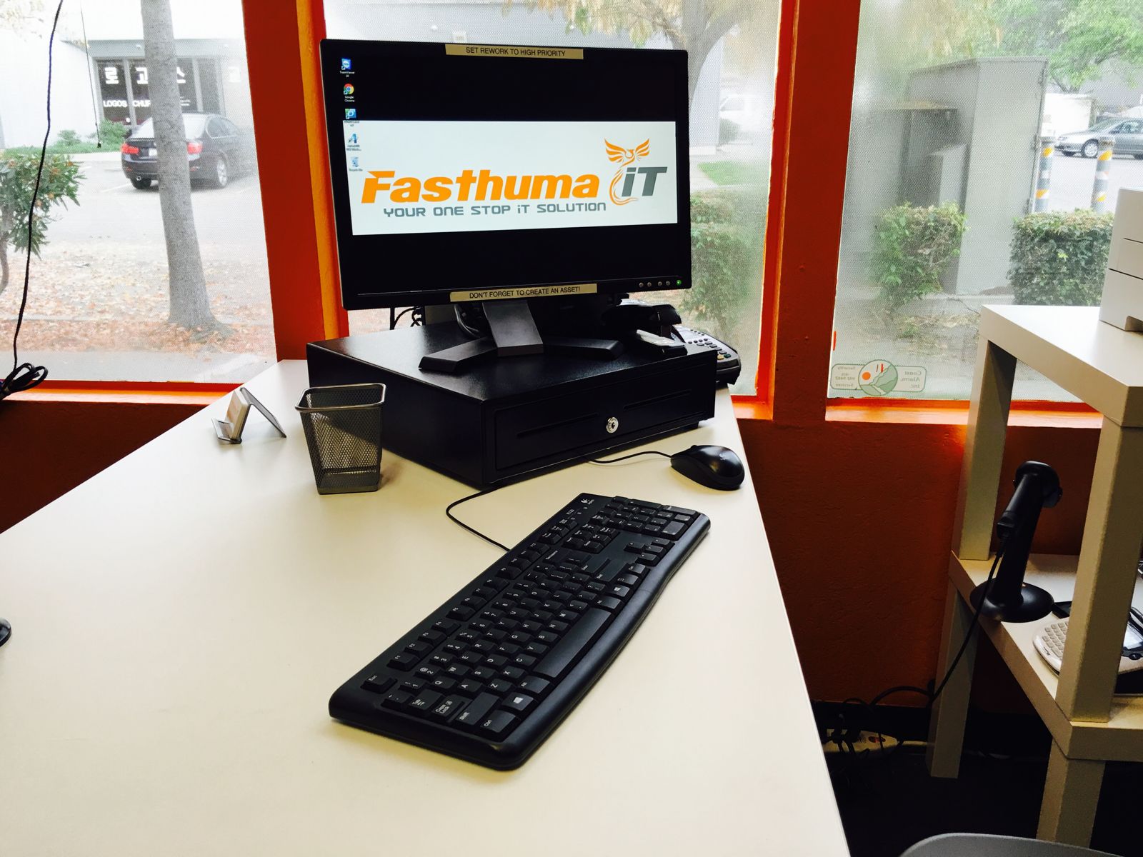 Fasthuma front desk: a computer showing the Fasthuma iT logo, a keyboard and mouse beside the front window.